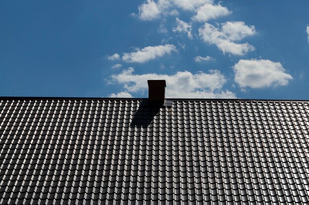 Nieuw metalen dak met schoorsteen op de achtergrond van de blauwe hemel,