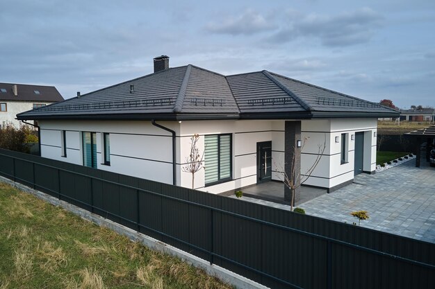 Foto nieuw woonhuis huisje en aangebouwde garage met grote verharde omheinde tuin op zonnige dag in moderne buitenwijk vastgoedconcept