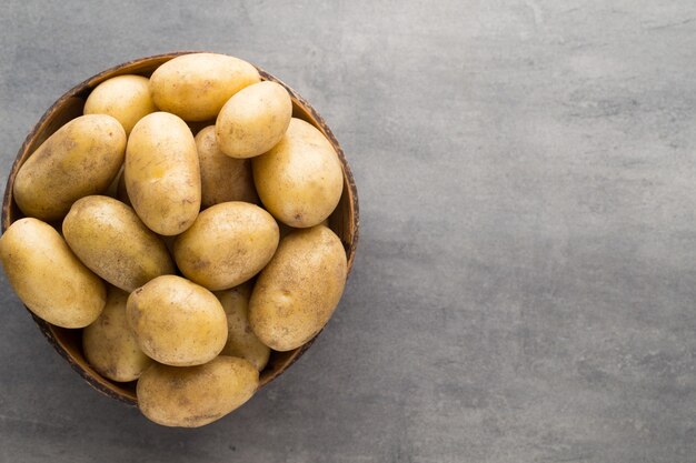 Nieuwe aardappel op de kom, grijze tafel.