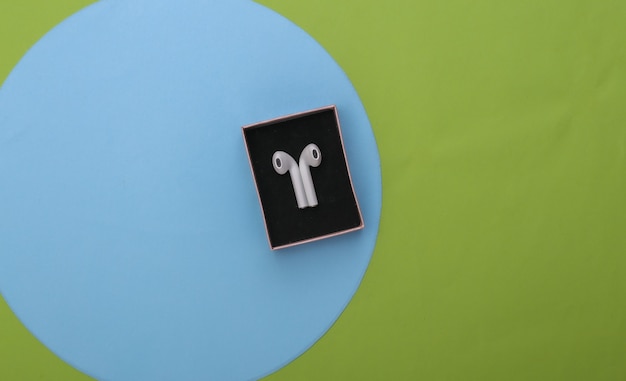 Foto nieuwe draadloze koptelefoon in een geschenkdoos op een blauwgroene pastelachtergrond. bovenaanzicht