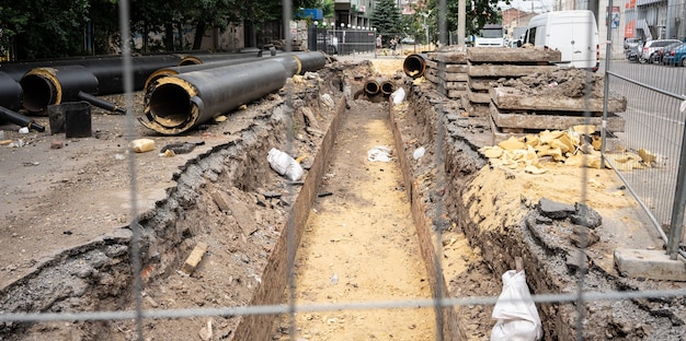 Nieuwe geïsoleerde zwarte waterleidingen en betonplaten op stadsweg in zomerdag