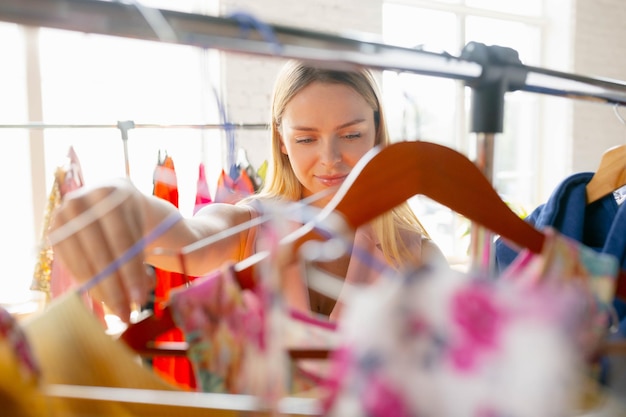 Nieuwe jurk. Slijtage, kledingwinkel tijdens uitverkoop, zomer- of herfstcollectie. Jonge vrouw op zoek naar nieuwe kleding. Concept van mode, stijl, aanbiedingen, emoties, verkoop, aankopen. Gloednieuw winkelen.