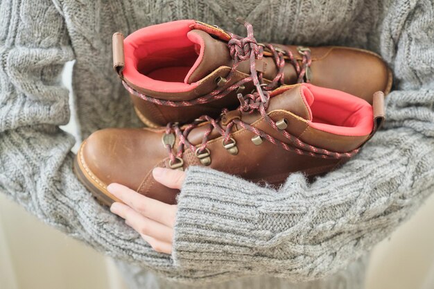 Nieuwe lederen bruine waterdichte wandelschoenen voor de herfst in handen van vrouwelijk, trendy schoeisel voor de winter. Schoenen uitpakken, online winkelen vanuit huis, schoenenwinkel