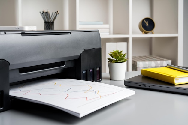 Nieuwe moderne printer en laptop in het kantoor op tafel.