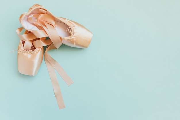 Nieuwe pastel beige balletschoenen met satijnen lint geïsoleerd op blauw