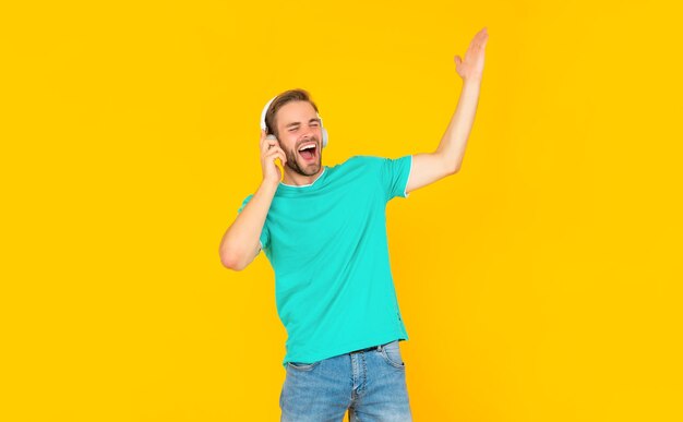 Nieuwe technologie. vrolijke zingende man in moderne oortelefoons. online onderwijs.