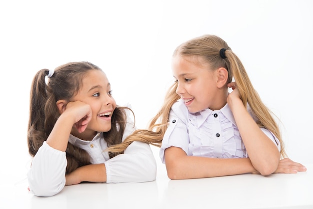 Nieuwe vrienden maken op school Gelukkige kleine vrienden praten tijdens de les Kleine schoolvrienden glimlachen naar elkaar geïsoleerd op wit Schattige vriendinnen genieten van goede vriendschapsrelaties