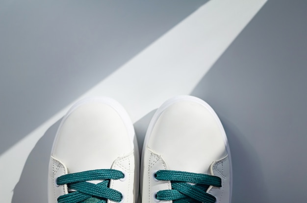 Nieuwe witte sneakers met groene veters op een witte achtergrond