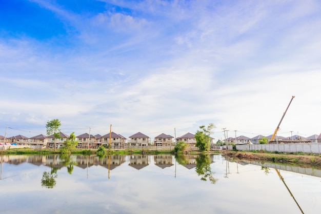 Nieuwe woningbouw reflectie met water in meer op woonwijk bouwplaats met wolken en blauwe hemel