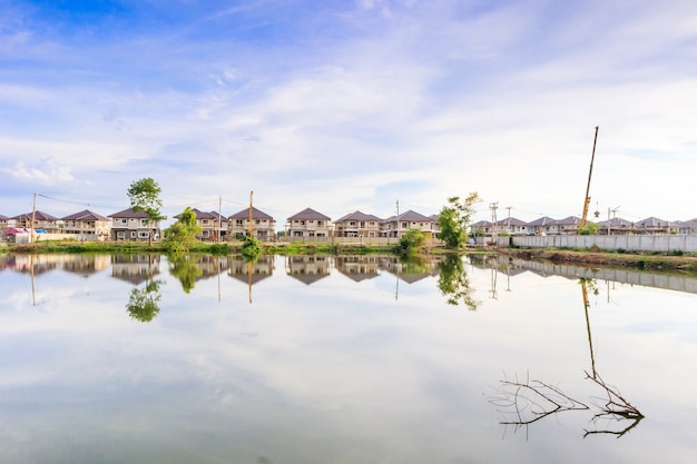 Nieuwe woningbouw reflectie met water in meer op woonwijk bouwplaats met wolken en blauwe hemel