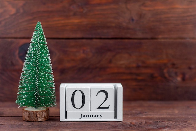 Nieuwjaar. 2 januari op de kalender. Kalender met een kleine kerstboom op een houten achtergrond. Winter