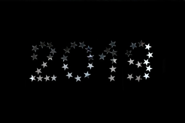 Foto nieuwjaar 2019 viering. de zilveren ster bestrooit confettien op zwarte achtergrond