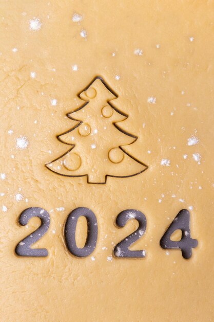 Foto nieuwjaar 2024 zelfgemaakte koekjes koken koekjes uitsnijden in de vorm van het nummer 2024 en kerstboom