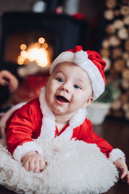 Nieuwjaar concept foto van een schattige kleine baby gekleed in kostuum van de Kerstman met open haard