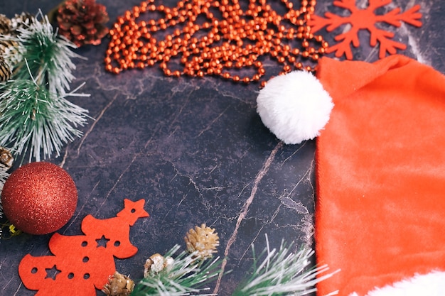 Nieuwjaar en kerstcadeaus. Selectieve aandacht. Kerstman hoed, dozen met geschenken, kralen, kerstspeelgoed op een donkere achtergrond.