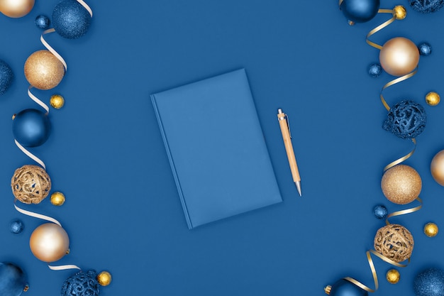 Nieuwjaar en Kerstmisdecoratie en notitieboekje en pen op blauwe document achtergrond. Wenslijst of doelen concept. Bovenaanzicht, plat lag, kopie ruimte. Trendy kleur van het jaar 2020.