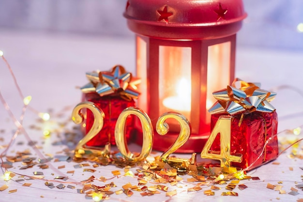 Nieuwjaar feest achtergrond gouden cijfers 2024 met heldere gloeiende lichten en een lamp met hete kaarsen