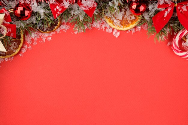 Nieuwjaar frame met een kerstboom en gekleurde decoraties op een rode lichte achtergrond