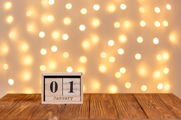 Nieuwjaar houten kalender 1 januari op houten achtergrond en verlichting background