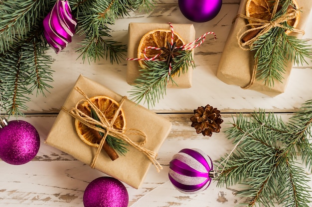 Nieuwjaar of Kerstmis achtergrond. handgemaakte geschenkdozen met stukjes sinaasappel en kaneel, vastgebonden met touw. witte houten achtergrond. bovenaanzicht.