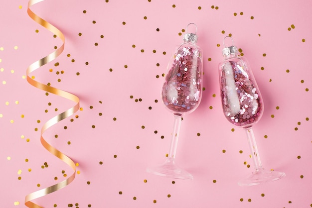 Foto nieuwjaar viering concept. boven boven bovenaanzicht foto van champagneglazen met confetti binnen geïsoleerd op pastel roze achtergrond met swirl en confetti