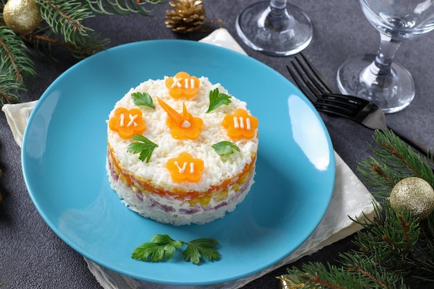 Nieuwjaars feestelijke salade in de vorm van een klok op een blauwe plaat op een grijze achtergrond closeup