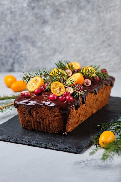 Foto nieuwjaars peperkoekcake met kumquat, gedroogde bessen en fruit. een feestelijk dessert versierd met vuren twijgen en verse bessen en fruit.