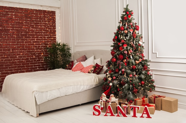 Nieuwjaarsdecor van de slaapkamer in de Scandinavische stijl Kerstboom Kerstman en bed met kussens Hygge Nieuwjaarsconcept Selectieve aandacht