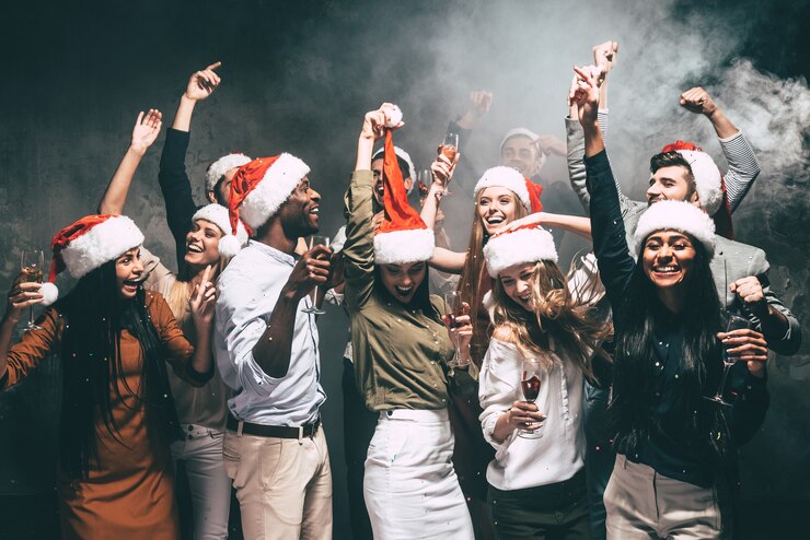 Foto nieuwjaarsfeest met vrienden. groep mooie jonge mensen in kerstmutsen die dansen en er gelukkig uitzien