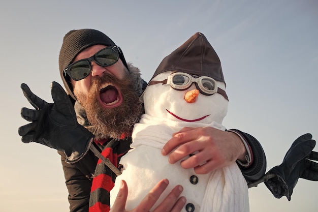 Nieuwjaarsman in het winterseizoen. Kerstman man met sneeuwpop in hoed. xmas vrije tijd en luchtvaart. Kerst man met baard op blij gezicht. Sneeuwpoppiloot, wintervakantieviering., reizen