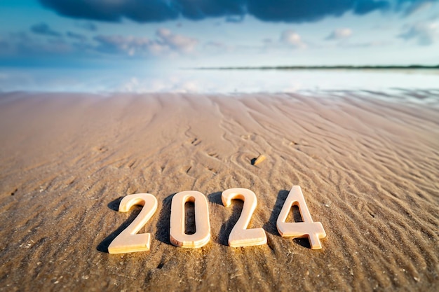 Nieuwjaarsnummers 2024 type 3D in het zand van een strand tussen de golven van de zee