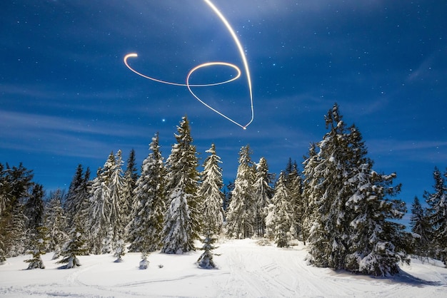 Nieuwjaarspad van een ster aan de nachtelijke hemel als achtergrond voor besneeuwde bomen in een prachtige vallei