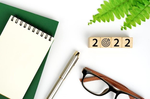 nieuwjaarsplan 2022 Plannen toetsenbord bril notebook en pen 2022 woord is geschreven op houtblok