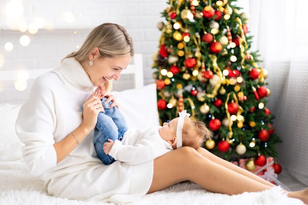 Nieuwjaarsvakantie Babyjongen met mooie moeder thuis met een kerstboom en versieringen