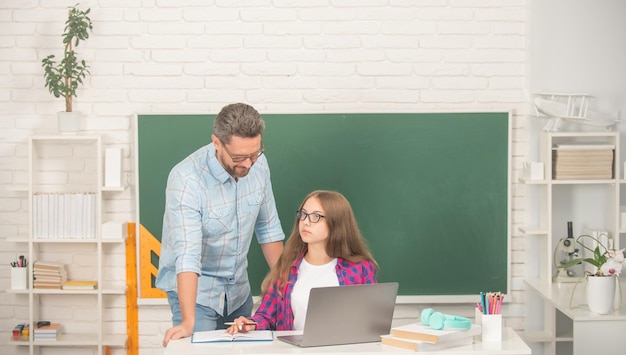 Nieuwsgierig kind en vader zitten in de klas met computer op schoolbord jeugd