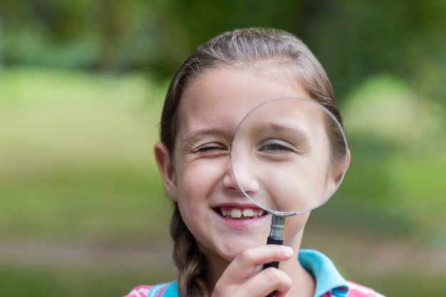 Nieuwsgierig meisje dat door vergrootglas kijkt