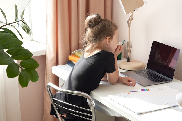 Foto nieuwsgierig meisje dat laptop met behulp van bij bureau