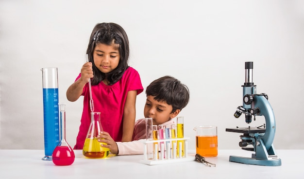 Nieuwsgierige kleine Indiase schoolkinderen of wetenschappers die wetenschap studeren, experimenteren met chemicaliën of microscoop in het laboratorium, selectieve focus