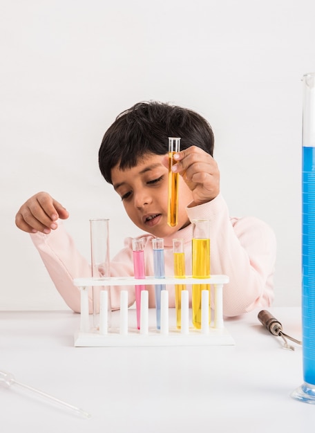 Nieuwsgierige kleine Indiase schoolkinderen of wetenschappers die wetenschap studeren, experimenteren met chemicaliën of microscoop in het laboratorium, selectieve focus