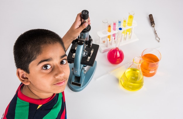 Nieuwsgierige kleine Indiase schoolkinderen of wetenschappers die wetenschap studeren, experimenteren met chemicaliën of microscoop in het laboratorium, selectieve focus