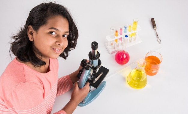 Nieuwsgierige kleine Indiase schoolkinderen of wetenschappers die wetenschap studeren, experimenteren met chemicaliën of microscoop in het laboratorium, selectieve focus