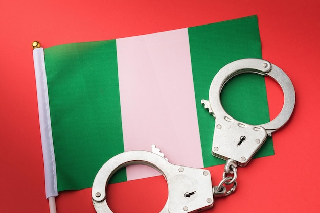 Nigeria flag and handcuffs on red background, concept of crime in Nigerian society