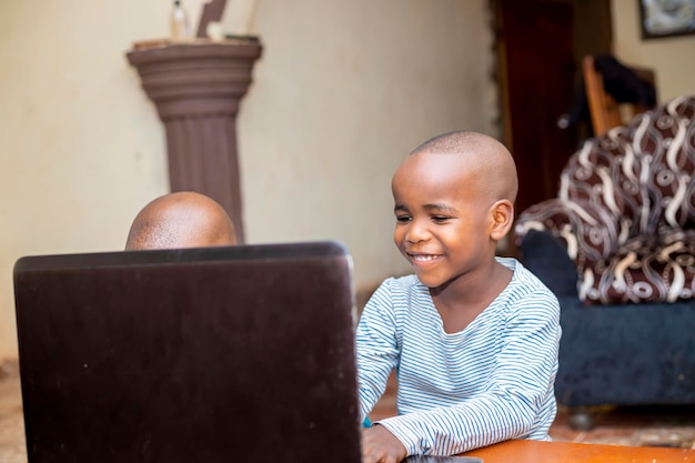 Nigeriaanse jongen die laptop gebruikt die thuis studeert en huiswerk maakt