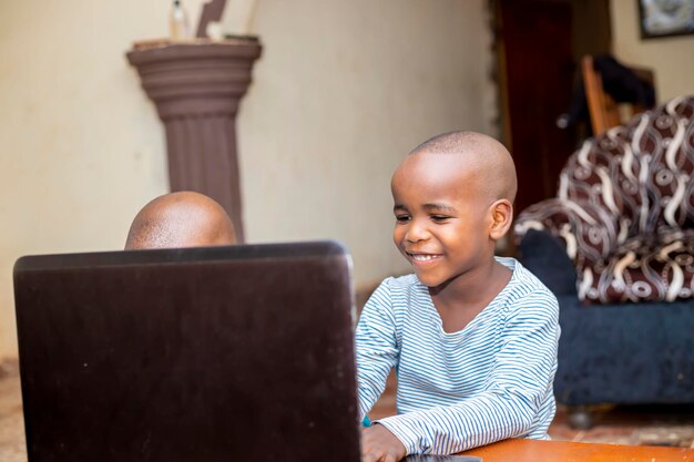 Nigerian boy using laptop studying from home doing homework