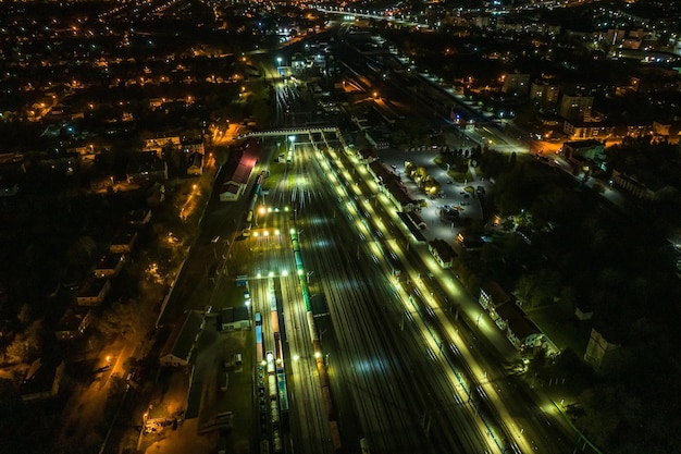 Night aerial view over long railway freight trains with lots of wagons stand on parking