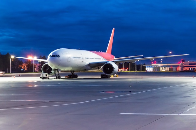 Night airport view and a large passenger plane in the parking lot before the flight.