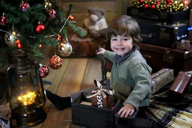 Ночью перед Рождеством маленький ребенок сидит на полу и играет с игрушками