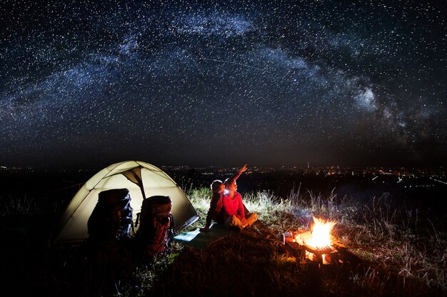 Foto campeggio notturno vicino alla città vicino al fuoco e alla tenda