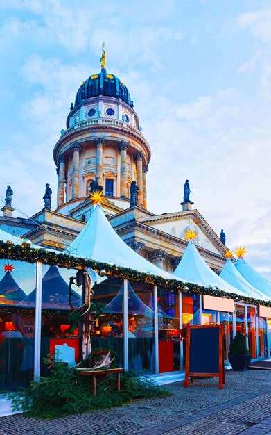 Night Christmas Market of Gendarmenmarkt in Winter Berlin, Germany. German street Xmas and holiday fair. Advent Decoration and Stalls with Crafts Items on the Bazaar.