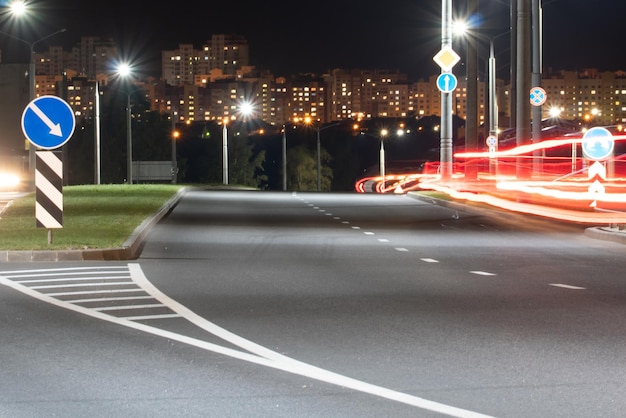 Night city light lines from cars cars in highway with blur motion Street view of the modern city at night A lot of light from car headlights advertising banners and night lights